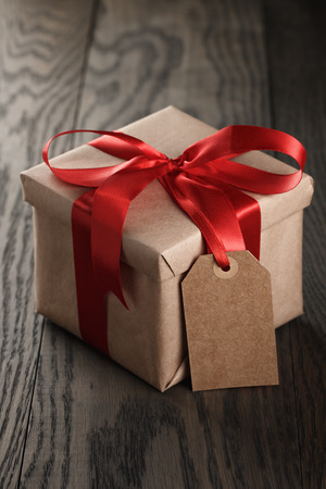 31539032 - rustic gift box with red ribbon bow and empty tag, on old wood table